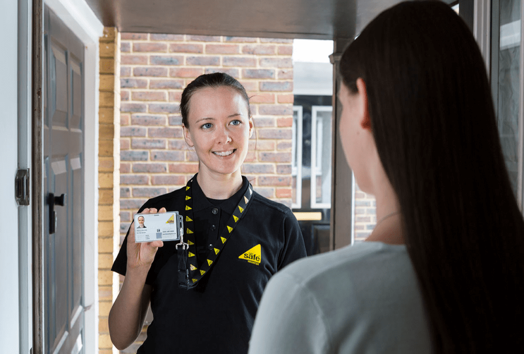 Female gas engineer standing at customer's door showing Gas Safe Register ID card