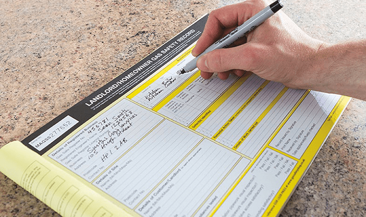 A gas engineer filling out a landlord's gas safety record check