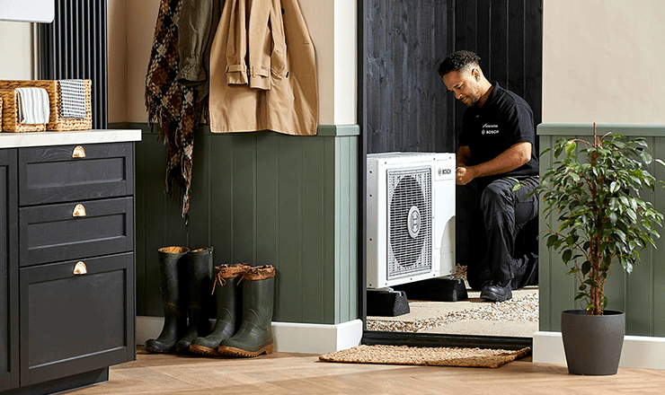 A heating engineer kneeling by a Worcester Bosch heat pump