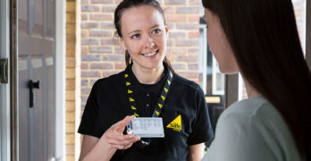 Female gas engineer showing Gas Safe ID card to customer