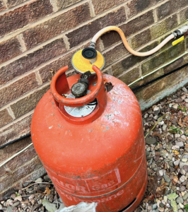 Corroded regulator on top of a red LPG cylinder